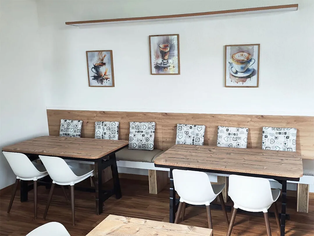 La panca con i cuscini e i tavoli in legno sotto i quadri delle tazze di caffè